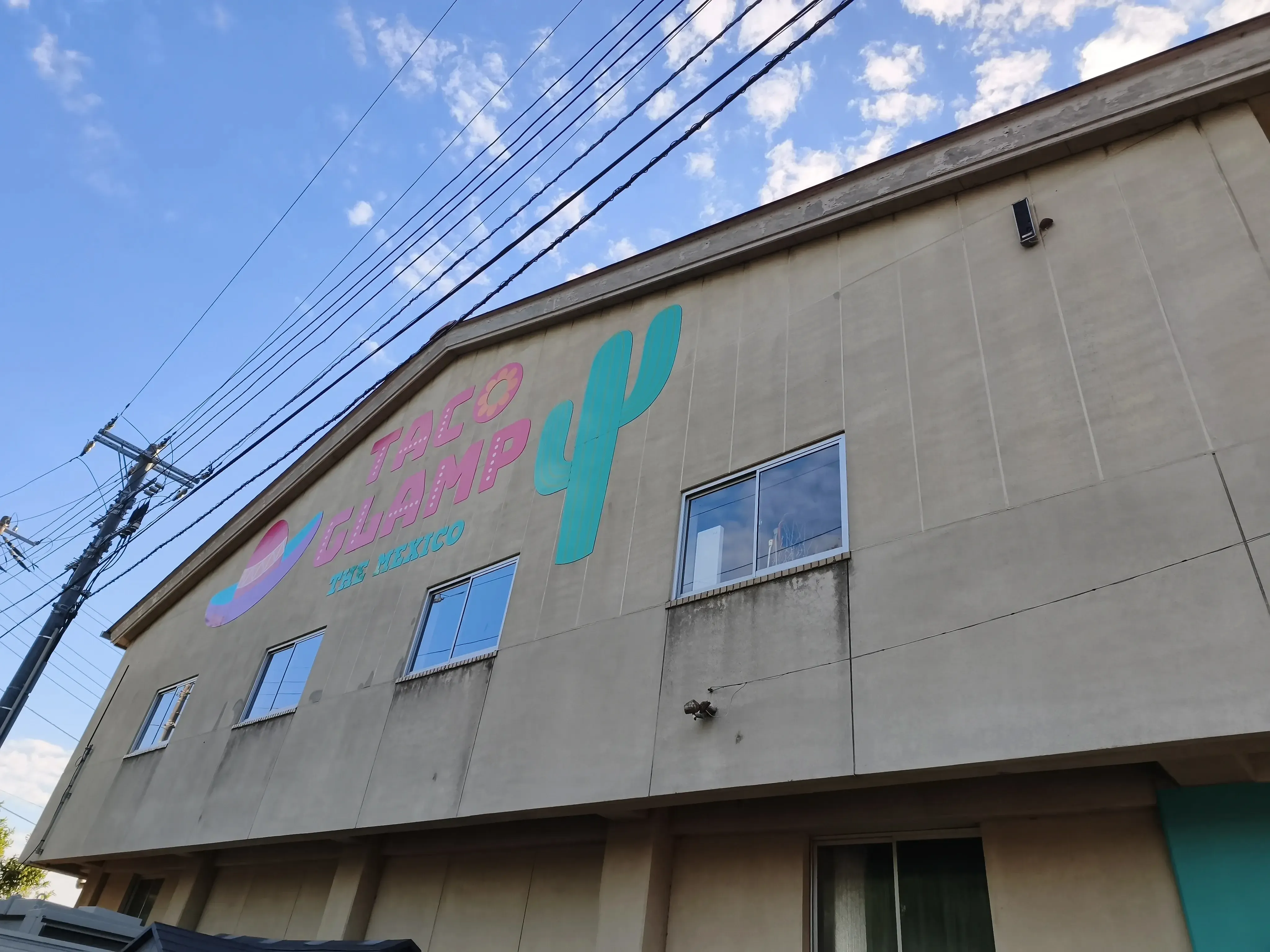 体育館のある校舎外壁。TACO GLAMPのロゴとサボテンが描かれている